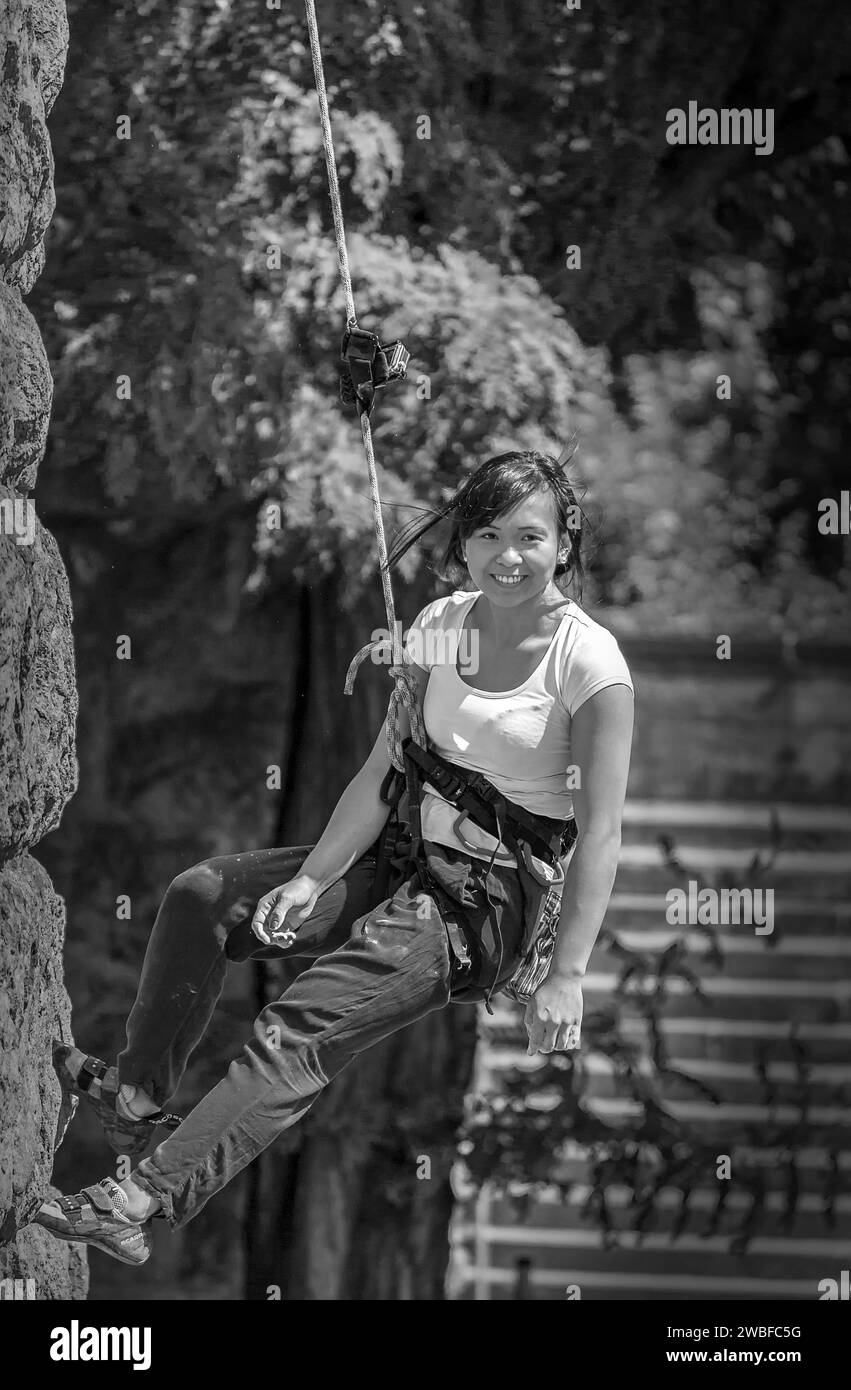 Une femme escaladant une paroi rocheuse, sécurisée avec une corde et un harnais, pont Hohenzollern, Cologne Deutz, Rhénanie du Nord-Westphalie, Allemagne Banque D'Images
