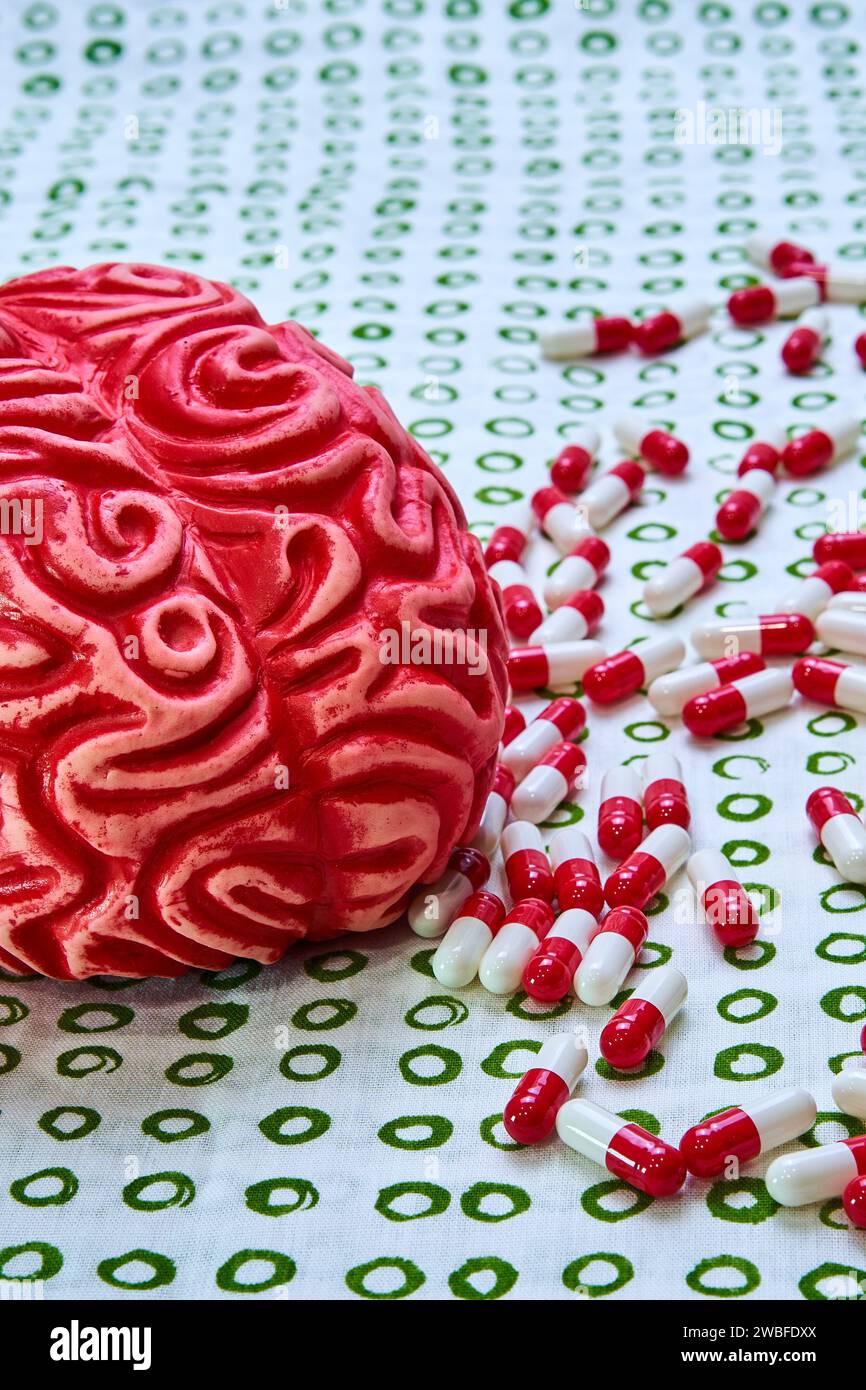 Cerveau de toxicomane humain rouge entouré de pilules et de capsules rouges et blanches. Banque D'Images