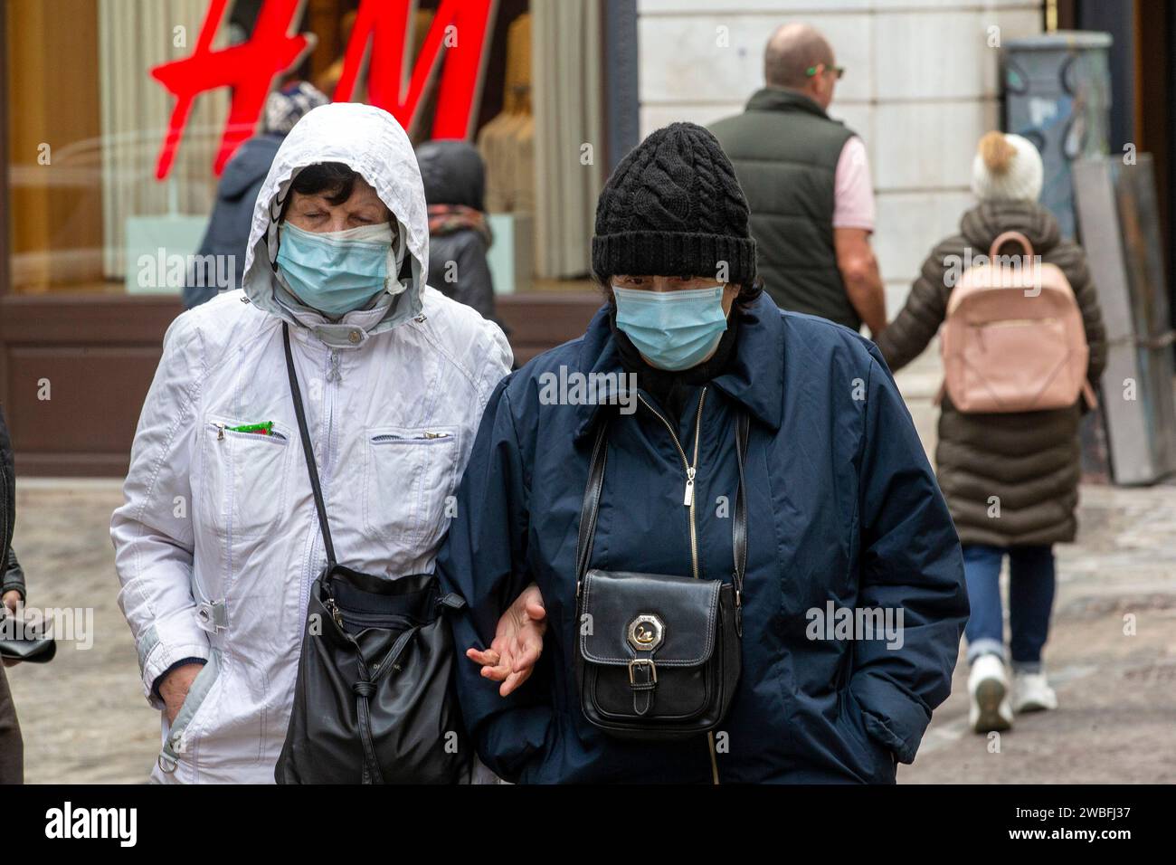 Athènes, Grèce. 10 janvier 2024. Un couple portant des masques se promène dans une rue à Athènes, en Grèce, le 10 janvier 2024. Le gouvernement grec a exhorté mercredi à une nouvelle augmentation des taux de vaccination contre le COVID-19 et la grippe, au milieu d’une vague d’infections ces dernières semaines. Crédit : Marios Lolos/Xinhua/Alamy Live News Banque D'Images