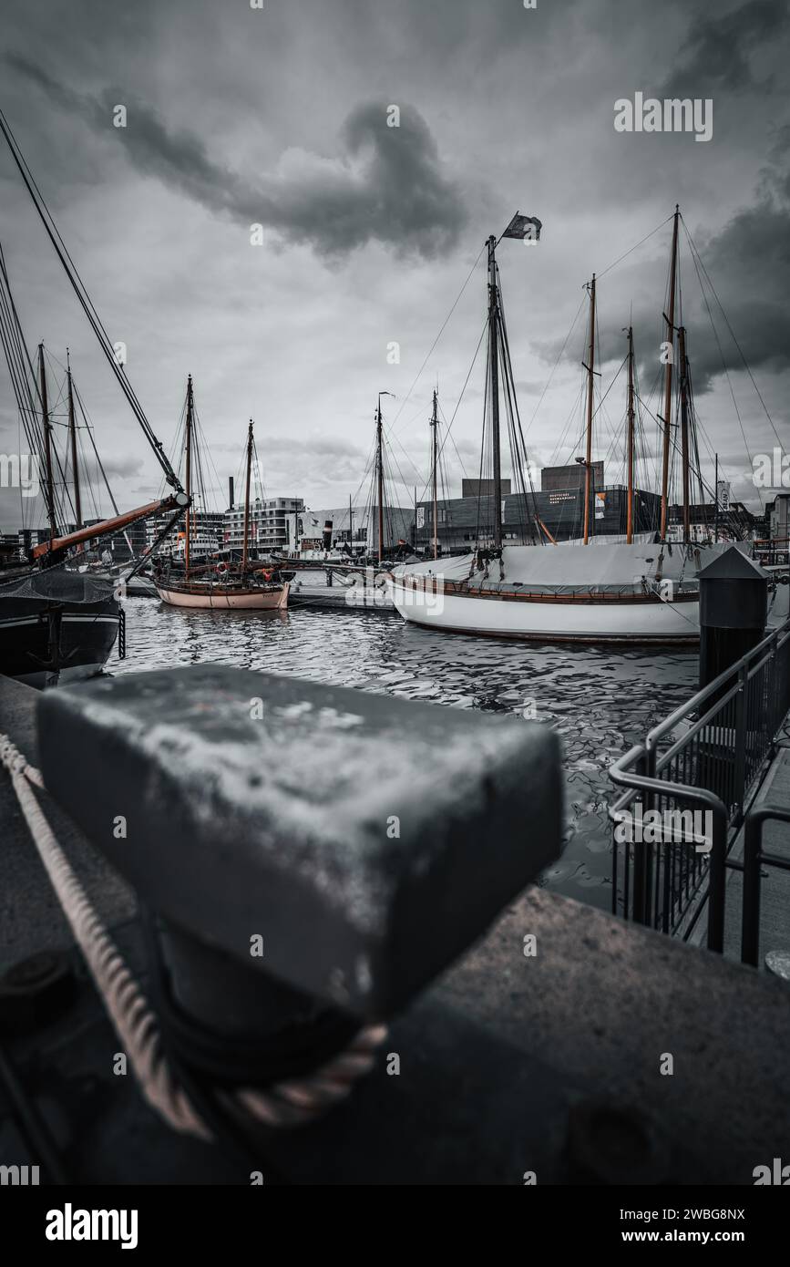 Un bateau de pêche vintage est amarré à un quai, avec un ciel gris moody fournissant une belle toile de fond Banque D'Images