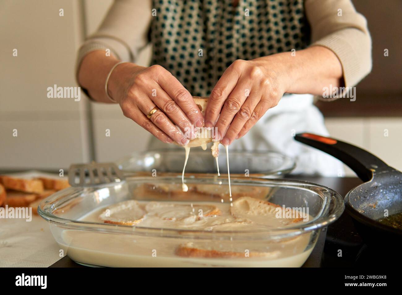 Gros plan sur les mains d'une femme âgée qui fait frire des toasts latino-français. Faire une recette traditionnelle sur une cuisinière électrique contemporaine Banque D'Images