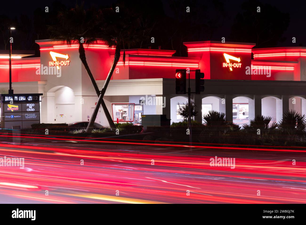 Brea, Californie, États-Unis - 24 octobre 2023 : le soir, la circulation coule sur Imperial Highway devant un restaurant de hamburgers In N Out. Banque D'Images