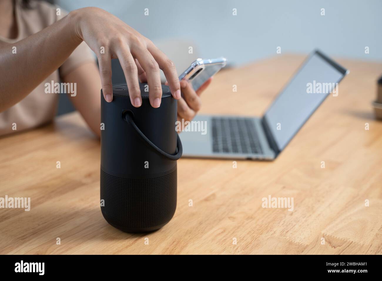 Jeune femme utilisant des haut-parleurs intelligents dans sa maison grâce à l'utilisation d'un téléphone intelligent. Banque D'Images