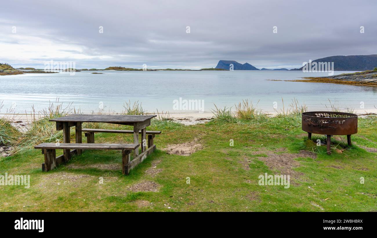 Coin salon sur la plage de Sommarøya, espace barbecue sur la rive de l'Atlantique Nord, à Troms, Norvège. Banc de parc en bois avec table, table à manger, cheminée Banque D'Images