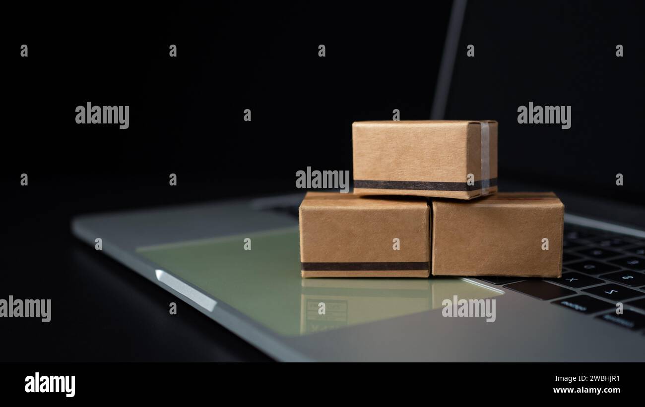 Boîtes sur un clavier d'ordinateur portable sur fond sombre. Idées sur les achats en ligne, les achats en ligne sont une forme de commerce électronique qui permet aux consommateurs de Banque D'Images