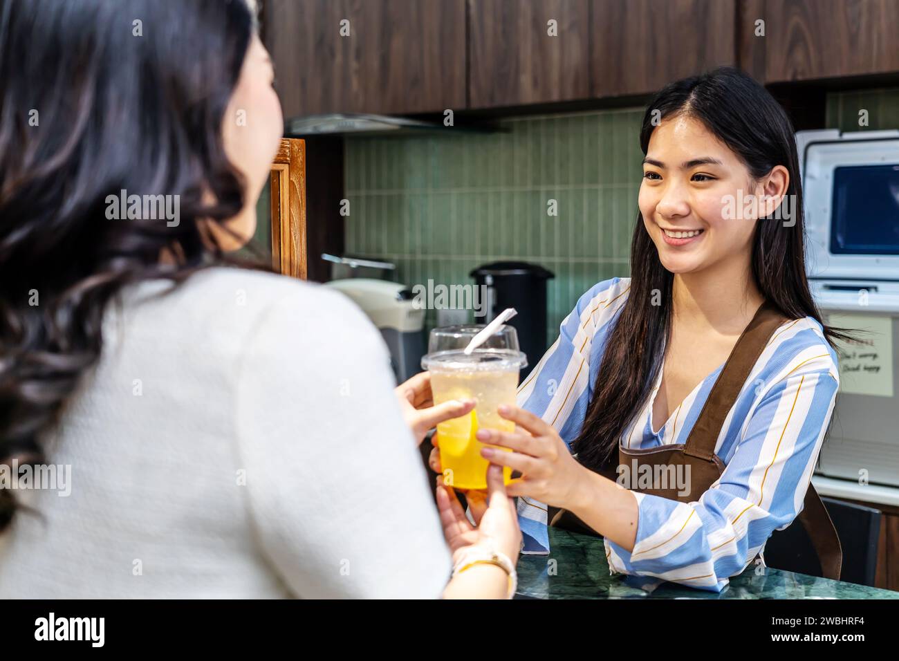 Jeune serveuse asiatique souriante dans un café avec le client pour le service, le paiement ou la commande sur le comptoir au café. Servir Banque D'Images