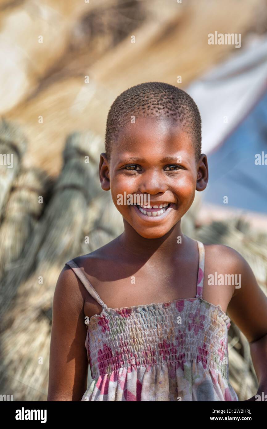 portrait d'un enfant africain heureux avec un sourire toothy dans la cour, la vie du village Banque D'Images