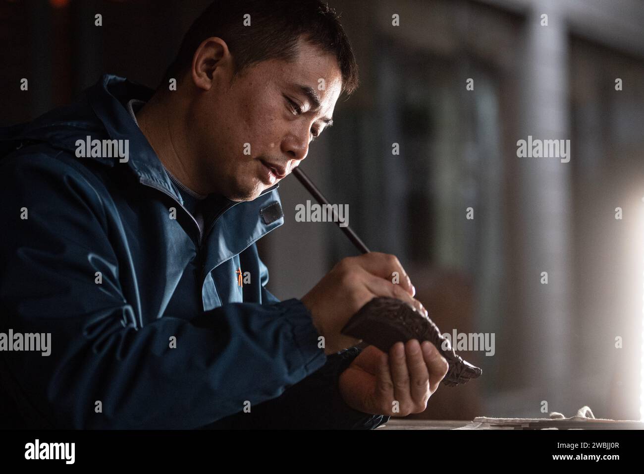 (240111) -- CHONGQING, 11 janv. 2024 (Xinhua) -- Yu Dahong grave sur un peigne en bois dans un atelier de l'usine Tanmujiang à Chongqing, dans le sud-ouest de la Chine, le 5 janvier 2024. L'artisanat traditionnel de fabrication de peigne en bois de Tanmujiang, qui combine l'habileté de la décoration de couleur, de la gravure, du laquage et de la dorure d'or, a été classé comme patrimoine culturel immatériel de la municipalité de Chongqing. En utilisant du buis, de l'ébène ou du bois de santal comme matériaux pour sculpter des motifs tels que des personnages, des fleurs et des oiseaux sur les peignes, l'artisanat a transformé l'article commun dans la vie quotidienne en une œuvre d'art avec des valeurs esthétiques. Banque D'Images