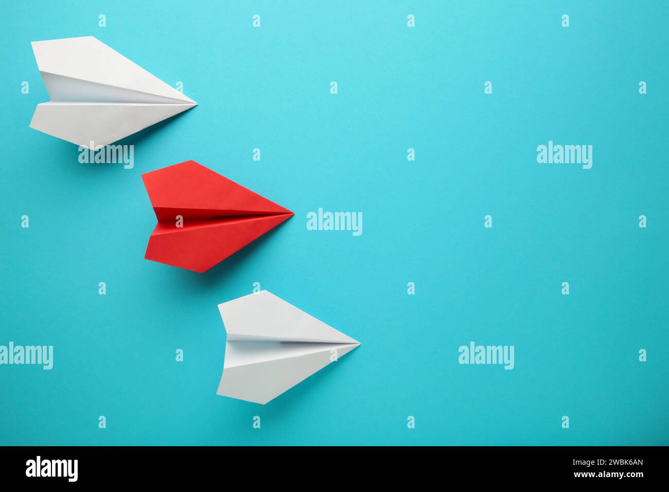 Avion de papier de couleur sur fond bleu, concept de concurrence d'entreprise. Vue de dessus Banque D'Images