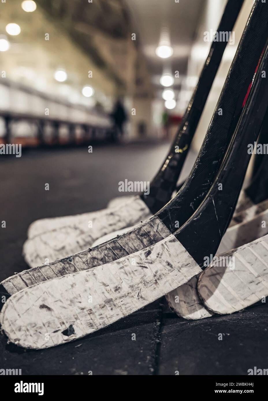 bâtons de hockey collés alignés appuyés sur un mur à la patinoire Banque D'Images