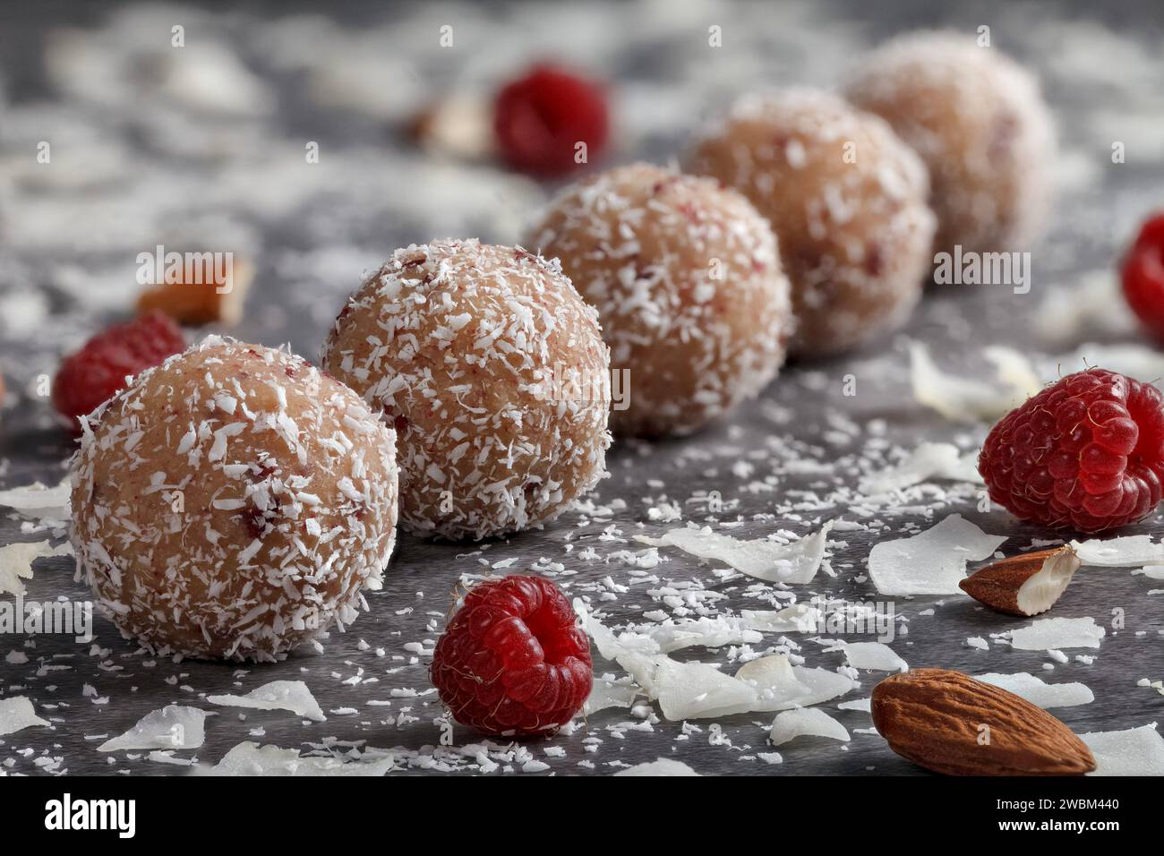 Truffes maison. Bonbons ronds. Truffe a amandes. Copeaux de noix de coco. Boules de chocolat sucré remplies d'amandes et de framboises sur un fond sombre Banque D'Images