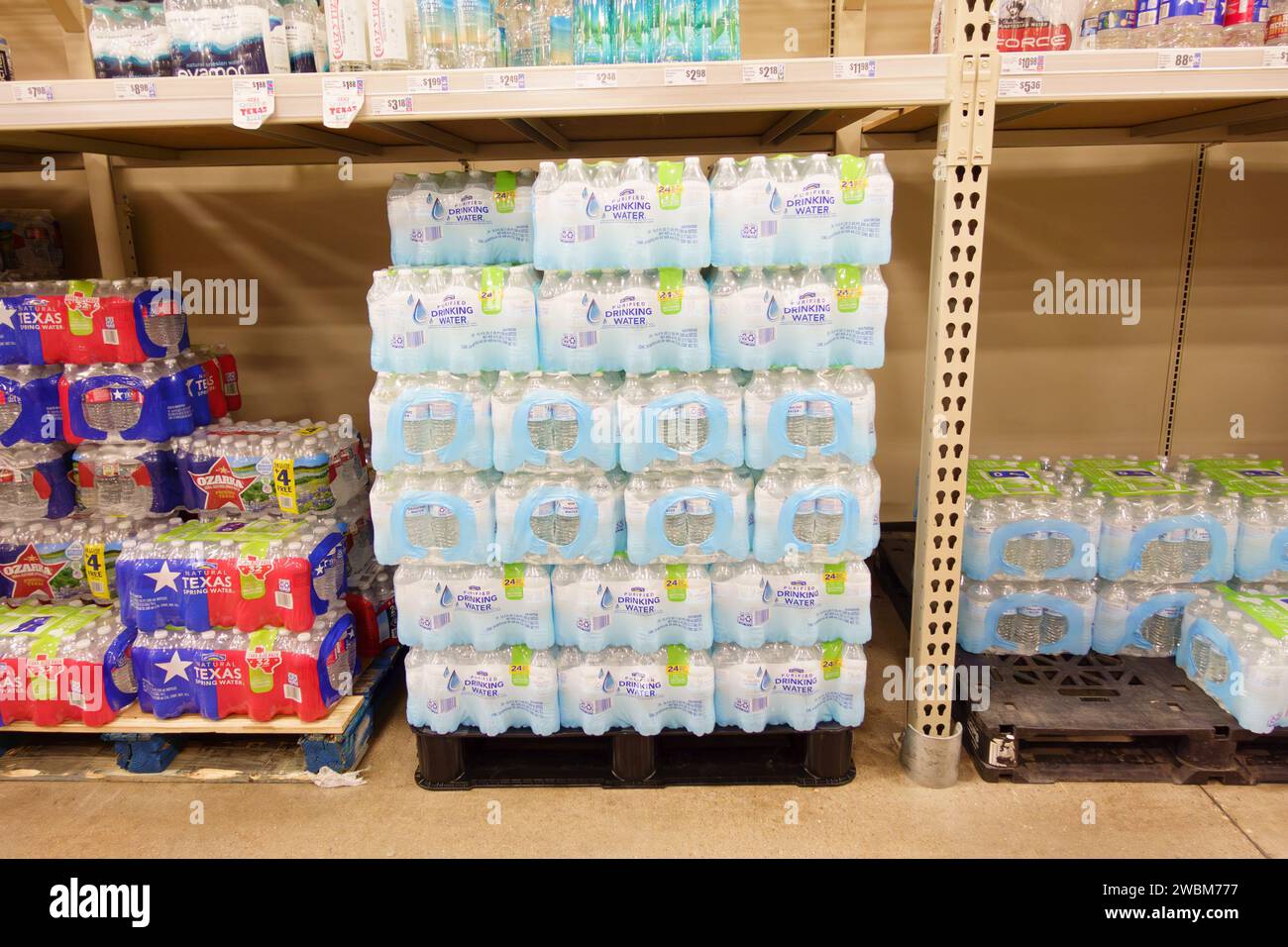 Paquets d'eau potable en bouteille sur palettes dans l'épicerie de supermarché Banque D'Images