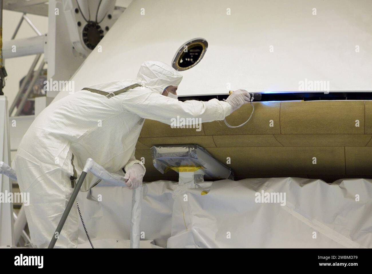 CAP CANAVERAL, Floride. – Dans l’installation d’entretien des charges utiles dangereuses du Kennedy Space Center de la NASA en Floride, un technicien inspecte l’alignement du bouclier thermique lorsqu’un pont roulant le soulève pour l’intégrer à la mission Aeroshell du Mars Science Laboratory (MSL) de la NASA (contenant le rover Curiosity compact de la taille d’une voiture). Plus tôt, l'aéroshell a été accouplé à l'étage de croisière, qui fournit de l'énergie solaire, des propulseurs pour la navigation et des échangeurs de chaleur au rover pendant son vol de la Terre à Mars. Le rover Curiosity dispose de 10 instruments scientifiques conçus pour rechercher des preuves sur l'existence de Mars Banque D'Images