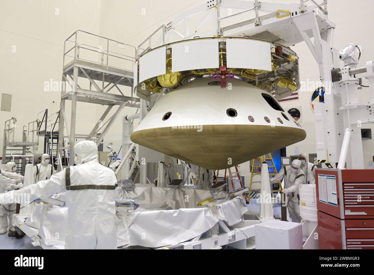 CAP CANAVERAL, Floride. – Dans le Payload Hazardous Servicing Facility du Kennedy Space Center de la NASA en Floride, les techniciens déplacent le support de bouclier thermique loin de sous le bouclier thermique après intégration avec la mission Aeroshell du Mars Science Laboratory (MSL) de la NASA, (contenant le rover Curiosity compact de la taille d’une voiture). Plus tôt, l'aéroshell a été accouplé à l'étage de croisière, qui fournit de l'énergie solaire, des propulseurs pour la navigation et des échangeurs de chaleur au rover pendant son vol de la Terre à Mars. Le rover Curiosity dispose de 10 instruments scientifiques conçus pour rechercher des preuves pour savoir si Mars a eu envi Banque D'Images