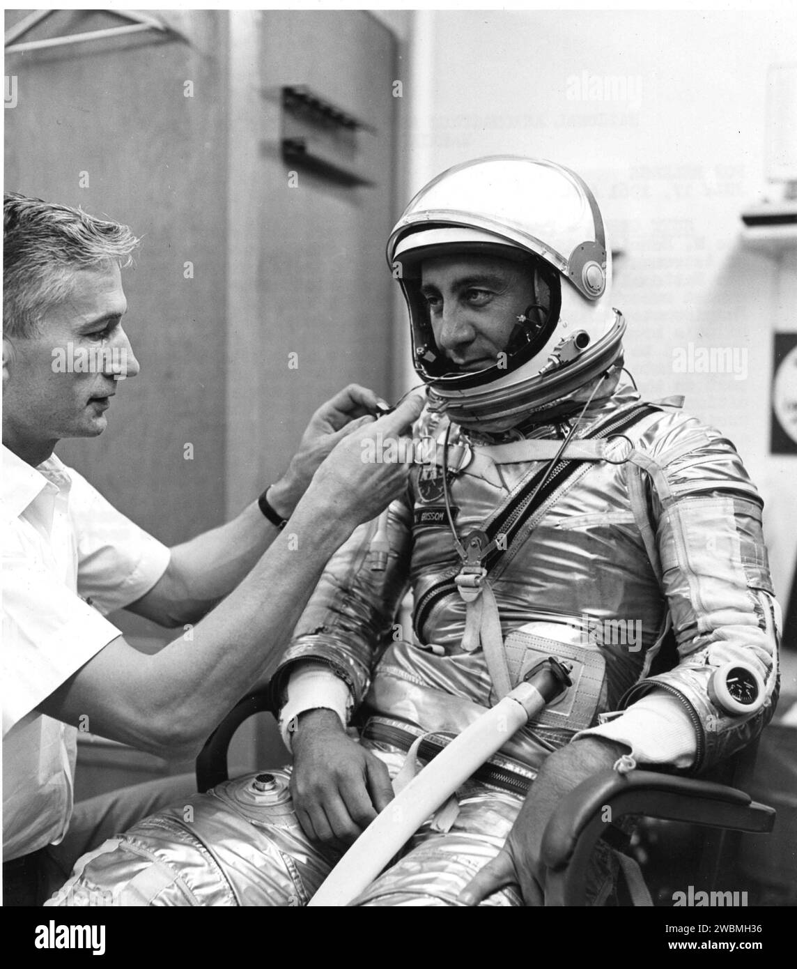 Joe W. Schidt, spécialiste de la combinaison de pression Mercury, ajuste un respiromètre sur le casque de l’astronaute Virgil I. Grissom lors de la répétition de pré-vol Liberty Bell 7. Le respiromètre surveille la respiration, fournit de l'oxygène, recycle l'air et permet d'envoyer des données télémétriques aux stations au sol. Banque D'Images