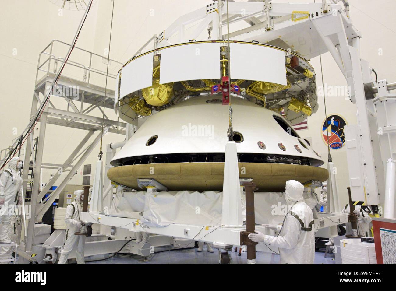 CAP CANAVERAL, Floride. – Dans le Payload Hazardous Servicing Facility du Kennedy Space Center de la NASA en Floride, sous les yeux vigilants des techniciens, un pont roulant soulève le bouclier thermique pour l’intégrer à la mission Aeroshell du Mars Science Laboratory (MSL) de la NASA (contenant le rover Curiosity compact de la taille d’une voiture). Plus tôt, l'aéroshell a été accouplé à l'étage de croisière, qui fournit de l'énergie solaire, des propulseurs pour la navigation et des échangeurs de chaleur au rover pendant son vol de la Terre à Mars. Le rover Curiosity dispose de 10 instruments scientifiques conçus pour rechercher des preuves sur la présence de Mars Banque D'Images