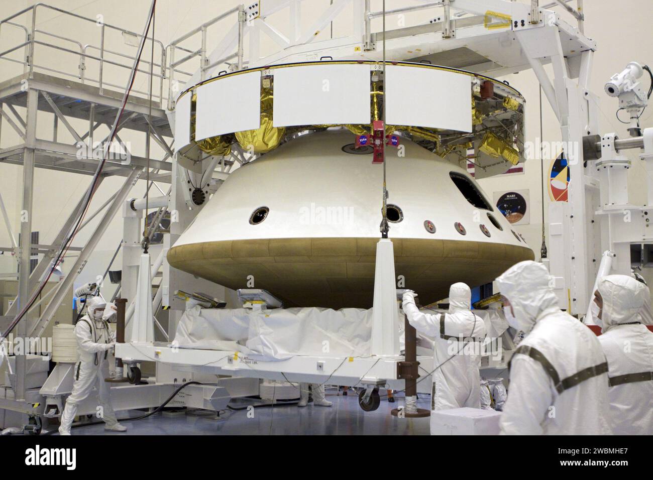 CAP CANAVERAL, Floride. – Dans le Payload Hazardous Servicing Facility du Kennedy Space Center de la NASA en Floride, à l’aide d’un pont roulant, les techniciens abaissent un porteur qui abritait le bouclier thermique, après intégration avec la mission Aeroshell du Mars Science Laboratory (MSL) de la NASA (contenant le rover Curiosity compact de la taille d’une voiture). Plus tôt, l'aéroshell a été accouplé à l'étage de croisière, qui fournit de l'énergie solaire, des propulseurs pour la navigation et des échangeurs de chaleur au rover pendant son vol de la Terre à Mars. Le rover Curiosity dispose de 10 instruments scientifiques conçus pour rechercher des preuves sur l'existence de Mars Banque D'Images