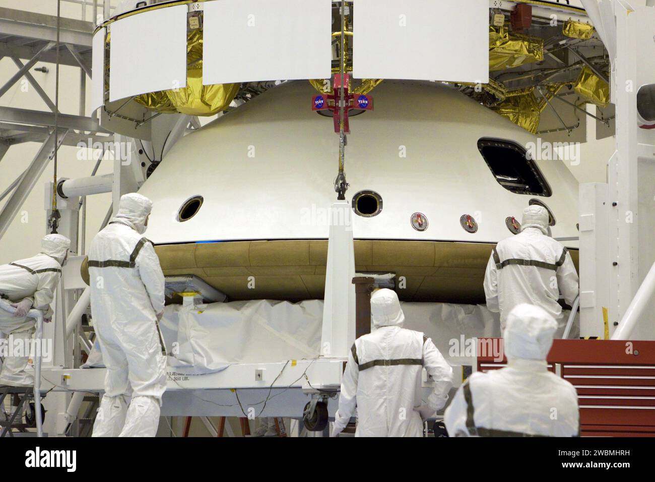 CAP CANAVERAL, Floride. – Dans le Payload Hazardous Servicing Facility du Kennedy Space Center de la NASA en Floride, les techniciens surveillent l’alignement du bouclier thermique lorsqu’un pont roulant le soulève pour l’intégrer à la mission Aeroshell du Mars Science Laboratory (MSL) de la NASA (contenant le rover Curiosity compact de la taille d’une voiture). Plus tôt, l'aéroshell a été accouplé à l'étage de croisière, qui fournit de l'énergie solaire, des propulseurs pour la navigation et des échangeurs de chaleur au rover pendant son vol de la Terre à Mars. Le rover Curiosity dispose de 10 instruments scientifiques conçus pour rechercher des preuves sur Mars Banque D'Images