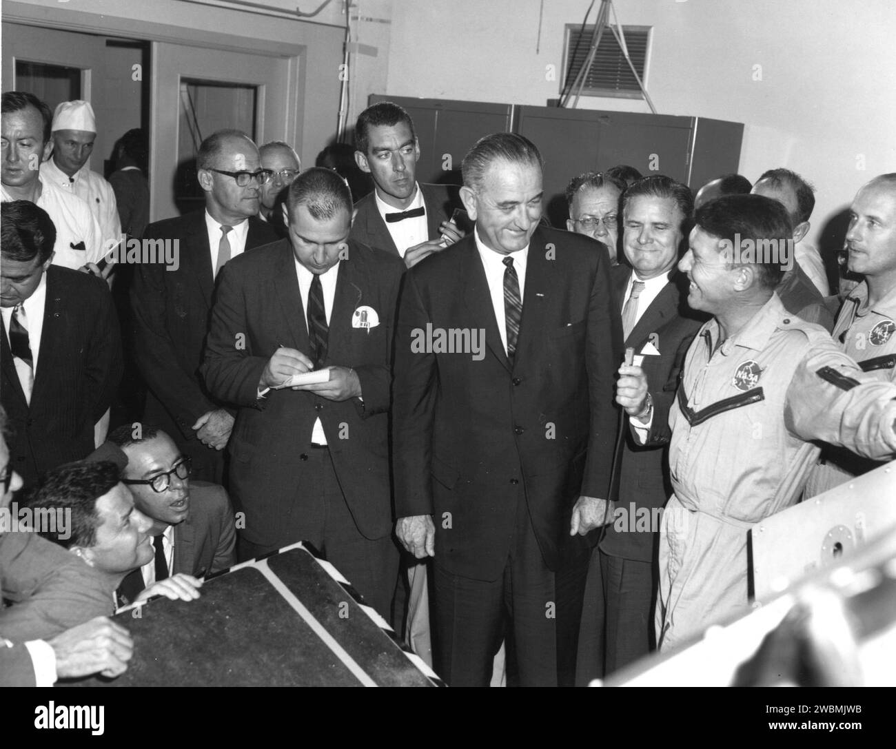 CENTRE SPATIAL KENNEDY, FLA. -- l'administrateur de la NASA James T. Webb tient le micro alors que le président Lyndon B. Johnson (au centre) et l'astronaute Walter Schirra (à droite) conversent lors de la visite du président au Kennedy Space Center. Banque D'Images