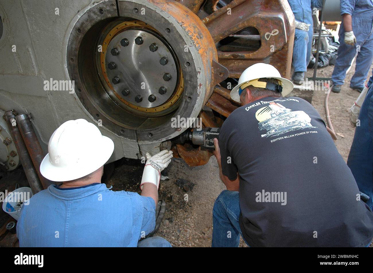 CENTRE SPATIAL KENNEDY, FLA. - Les ouvriers attachent le pignon géant et l'engrenage attaché au Crawler-transporter. Le pignon d'entraînement fait tourner le tapis sur le CT. Le pignon est couplé à l'engrenage qui se fixe au moteur d'entraînement. Le CT se déplace sur huit bandes de roulement à chenilles, chacune contenant 57 patins de bande de roulement, pour un poids combiné de 957 600 livres. Le CT transporte la navette spatiale au-dessus de sa plate-forme de lancement mobile, ajoutant 12 millions de livres supplémentaires, du bâtiment d'assemblage des véhicules à la plate-forme de lancement. Les ingénieurs du système CT de la NASA et de la United Space Alliance (USA) et les techniciens américains réparent le sp Banque D'Images