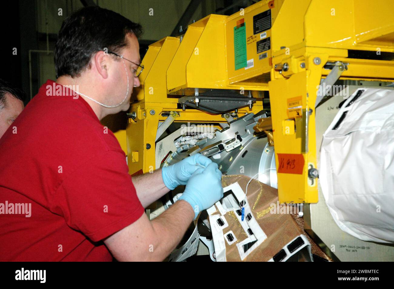 CENTRE SPATIAL KENNEDY, FLA. - Dans l'allée de transfert arrière de l'Orbiter Processing Facility Bay 3, Todd Dugan, technicien de United Space Alliance, commence à fixer la couverture du système de protection thermique (TPS) au système de capteur de flèche Orbiter (OBSS). L'installation de l'isolation conclut la fermeture du TPS avant l'installation de la flèche dans l'orbiteur Discovery. L’OBSS est l’une des nouvelles mesures de sécurité pour le retour en vol, en équipant la navette de caméras et de systèmes laser pour inspecter le système de protection thermique de la navette dans l’espace. La découverte est désignée comme le Retour à FL Banque D'Images