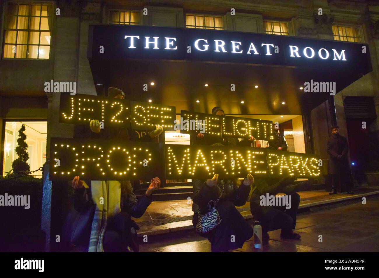 Londres, Royaume-Uni. 11 janvier 2024. Les militants de PETA organisent une manifestation devant les Globe Travel Awards à l’hôtel JW Marriott Grosvenor dans Park Lane à Londres, tenant des panneaux lumineux indiquant « Jet2, See the Light, Drop Marine Parks ». L’action fait partie de la campagne en cours de PETA exhortant Jet2, le plus grand voyagiste du Royaume-Uni, à abandonner les parcs marins qui retiennent les cétacés captifs de ses forfaits vacances. Crédit : Vuk Valcic/Alamy Live News Banque D'Images