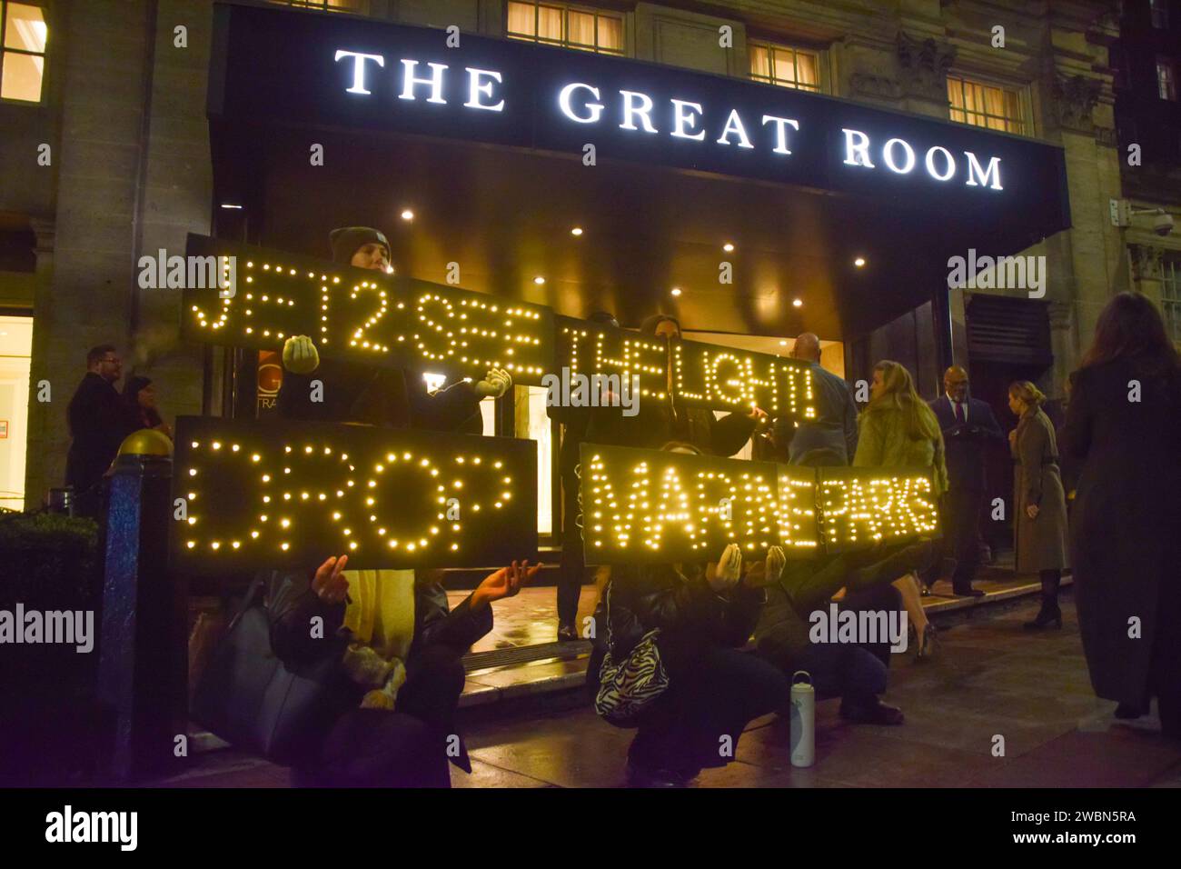 Londres, Royaume-Uni. 11 janvier 2024. Les militants de PETA organisent une manifestation devant les Globe Travel Awards à l’hôtel JW Marriott Grosvenor dans Park Lane à Londres, tenant des panneaux lumineux indiquant « Jet2, See the Light, Drop Marine Parks ». L’action fait partie de la campagne en cours de PETA exhortant Jet2, le plus grand voyagiste du Royaume-Uni, à abandonner les parcs marins qui retiennent les cétacés captifs de ses forfaits vacances. Crédit : Vuk Valcic/Alamy Live News Banque D'Images