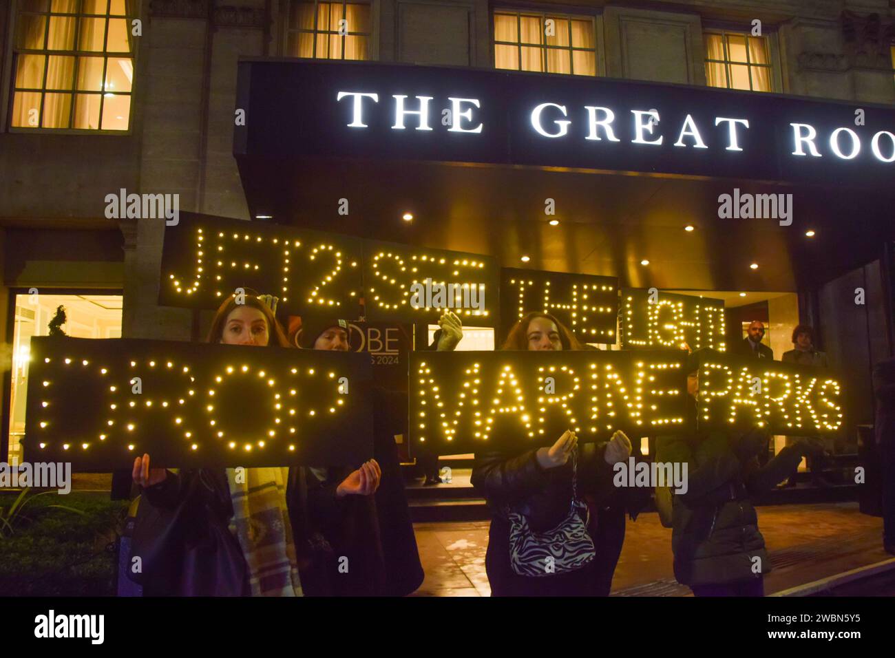 Londres, Royaume-Uni. 11 janvier 2024. Les militants de PETA organisent une manifestation devant les Globe Travel Awards à l’hôtel JW Marriott Grosvenor dans Park Lane à Londres, tenant des panneaux lumineux indiquant « Jet2, See the Light, Drop Marine Parks ». L’action fait partie de la campagne en cours de PETA exhortant Jet2, le plus grand voyagiste du Royaume-Uni, à abandonner les parcs marins qui retiennent les cétacés captifs de ses forfaits vacances. Crédit : Vuk Valcic/Alamy Live News Banque D'Images