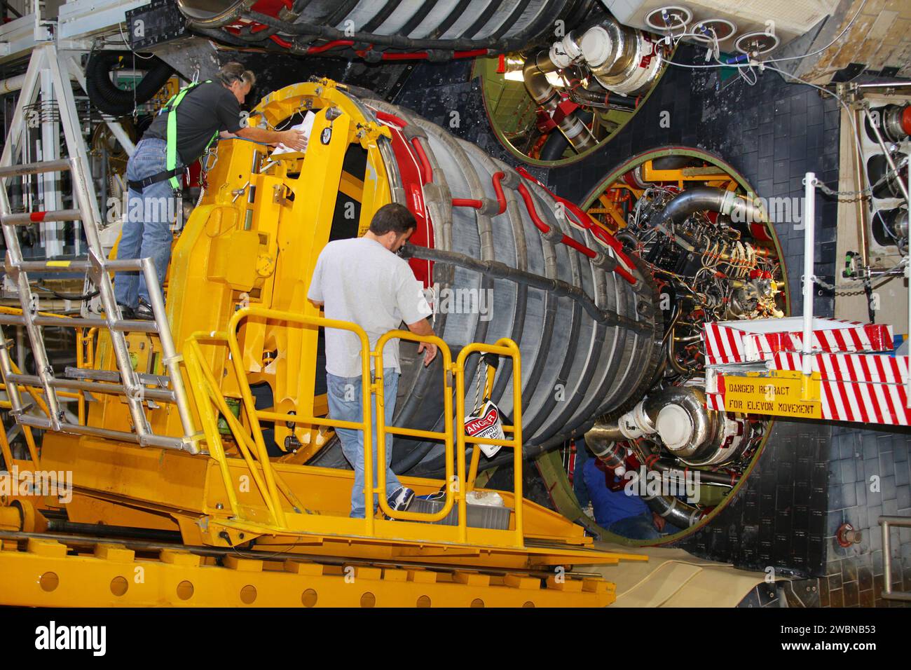 CAP CANAVERAL, Floride. -- dans Orbiter Processing Facility-2 du Kennedy Space Center de la NASA en Floride, les techniciens surveillent les progrès lorsqu'ils utilisent un chariot élévateur Hyster pour positionner un dispositif de dépose de moteur sur le moteur #3 de la navette spatiale Atlantis. À l'intérieur de la section arrière, un technicien déconnecte les conduites hydrauliques, hydrauliques et électriques. Le chariot élévateur sera utilisé pour déposer le moteur et le transporter jusqu'à l'atelier moteur pour une utilisation future éventuelle. Chacun des trois moteurs principaux de la navette spatiale mesure 14 pieds de long et pèse 7 800 livres. Le retrait des moteurs principaux de la navette spatiale fait partie de la transition et du retrait Banque D'Images