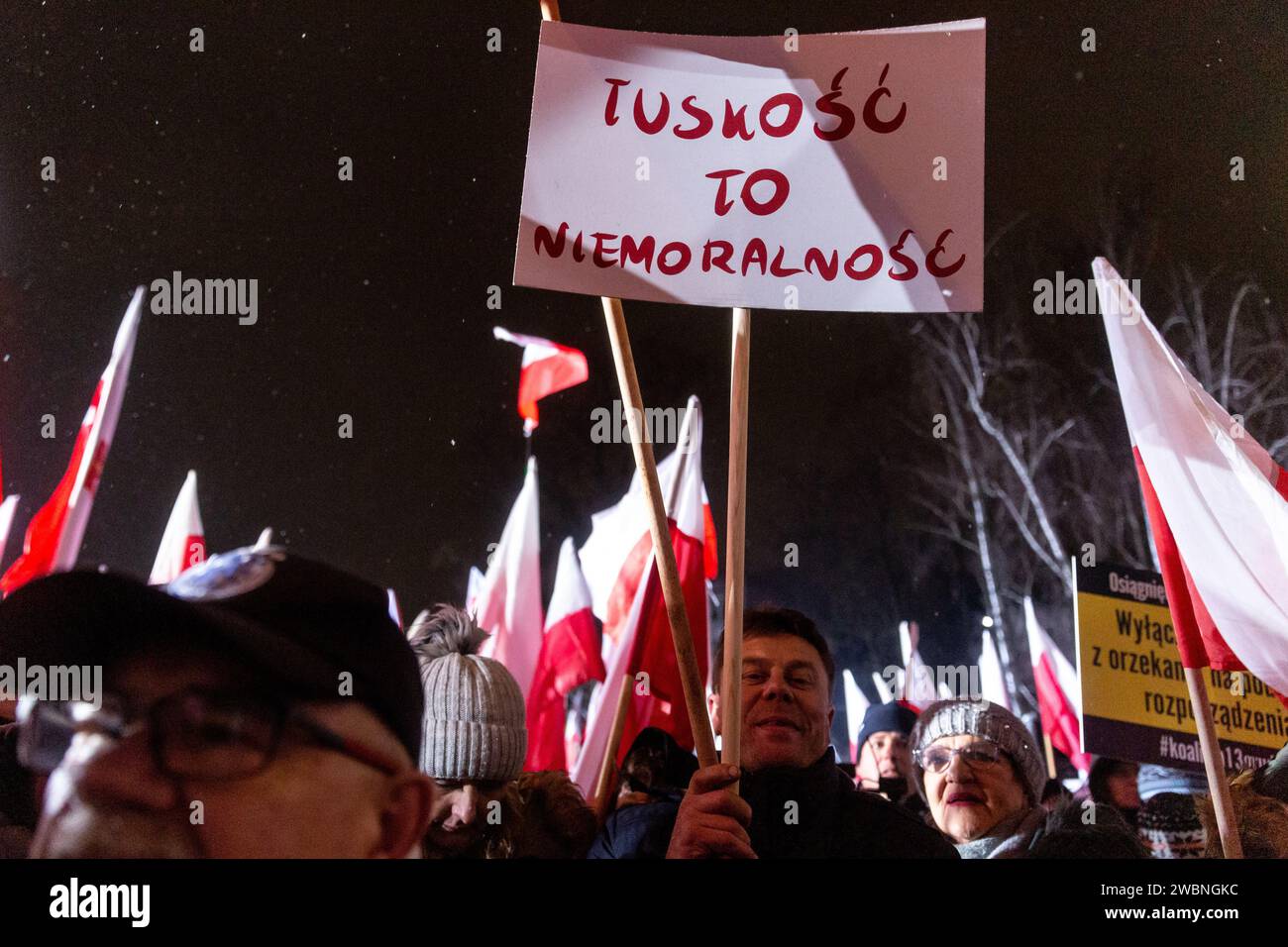 Varsovie, Pologne, 11 janvier 2024. Foules de gens, tenant des drapeaux nationaux polonais et une bannière qui disent "Tusk-ality is immorality", dirigée par droit et Justice (prawo i Sprawiedliwość - pis) les dirigeants des partis politiques protestent devant le bâtiment du Parlement polonais contre les changements dans les médias publics en Pologne et dans la protection de la démocratie - disent les politiciens du pis. Le parti droit et Justice a régné en Pologne pendant 8 ans jusqu'à ce qu'ils perdent les dernières élections en octobre 2023. Le parti devient maintenant une force d'opposition de droite contre une coalition dirigeante plus centriste et libérale, où la principale force politique Banque D'Images