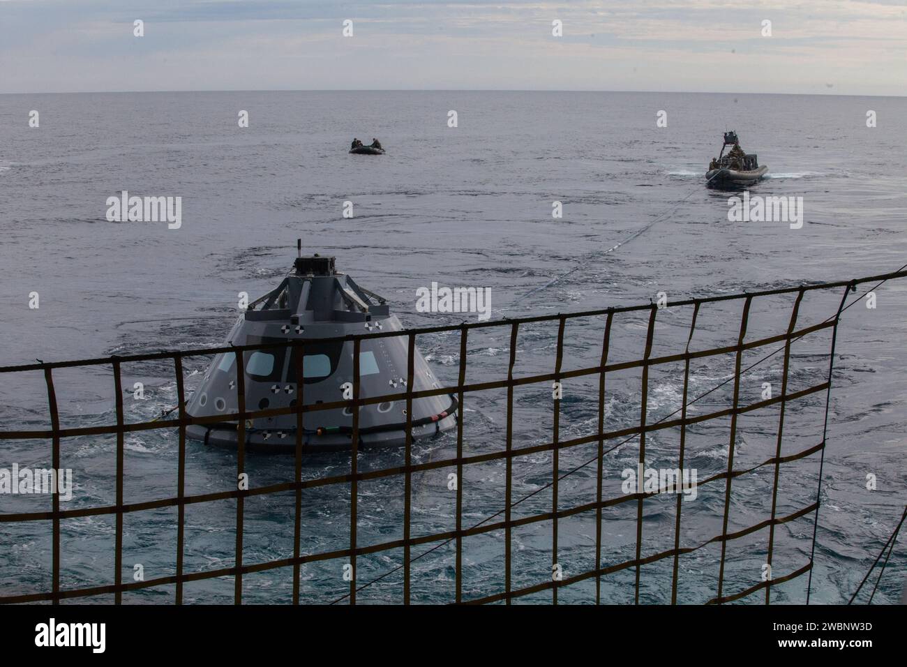 Les plongeurs et le personnel de l'US Navy dans une coque rigide des lignes d'attache de poignée de bateau gonflable fixées à un module d'équipage Orion d'essai pendant le test de récupération 5 en cours dans l'océan Pacifique au large de la Californie, alors que les équipes de la NASA et de la Navy évaluent les procédures de récupération, les embarcations, le personnel et le matériel pour les opérations de mission dans l'espace lointain Banque D'Images