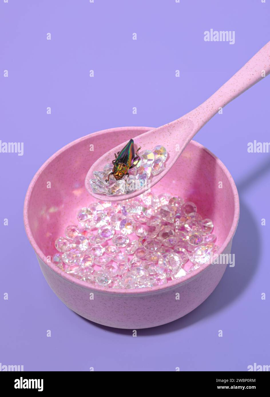 Un Bowlful ou Iridescent Diamonds dans un bol rose pastel et un beau bogue iridescent Beetle sur une cuillère Banque D'Images