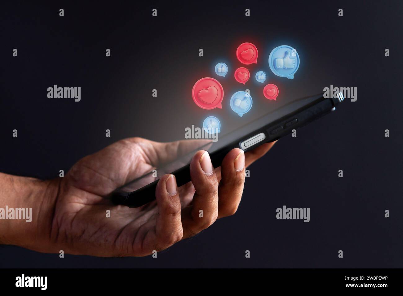 Main tenant le smartphone et l'icône de cœur et de pouces vers le haut. Concept de médias sociaux. Banque D'Images