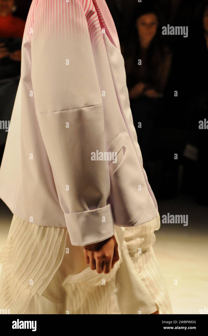 Vue de profil d'une veste de femme rose clair structurée avec des rayures dégradés rouges sur une smock mode crème fluide Runway show Raffles Showcase MBFWA Banque D'Images