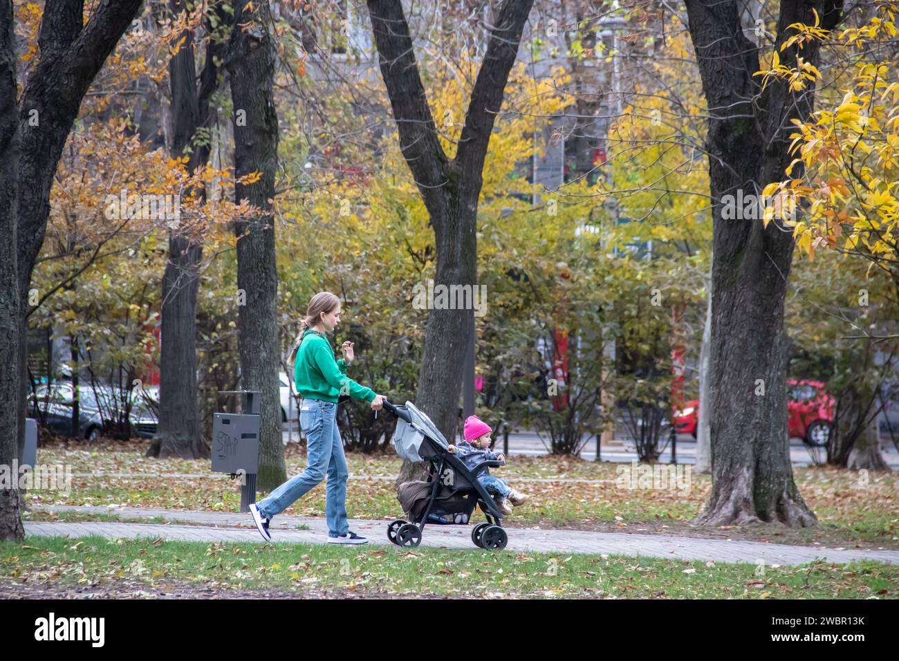 Jeune parent (maman) emmenant son enfant au parc public pour enfants à l'automne en octobre Banque D'Images