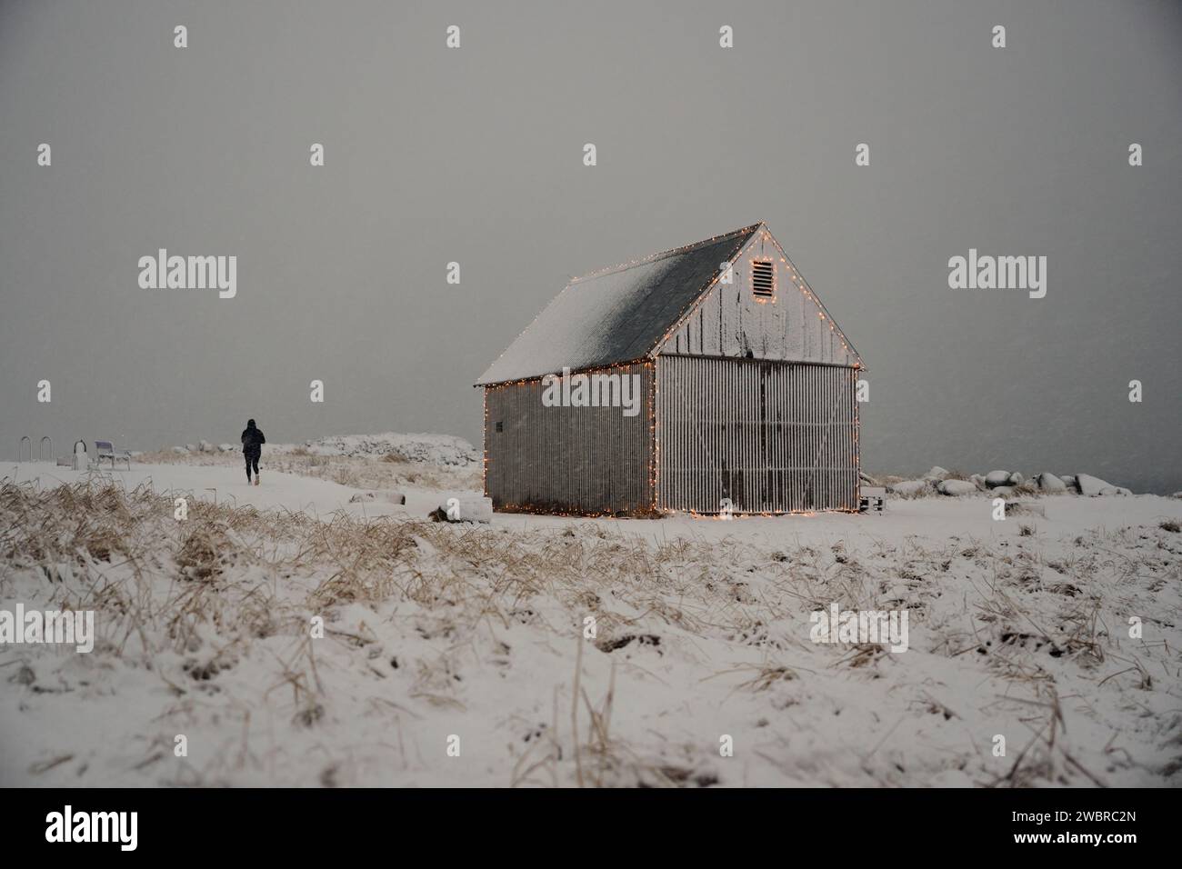 Personne marchant près du hangar dans la vallée enneigée sur le champ de neige Banque D'Images