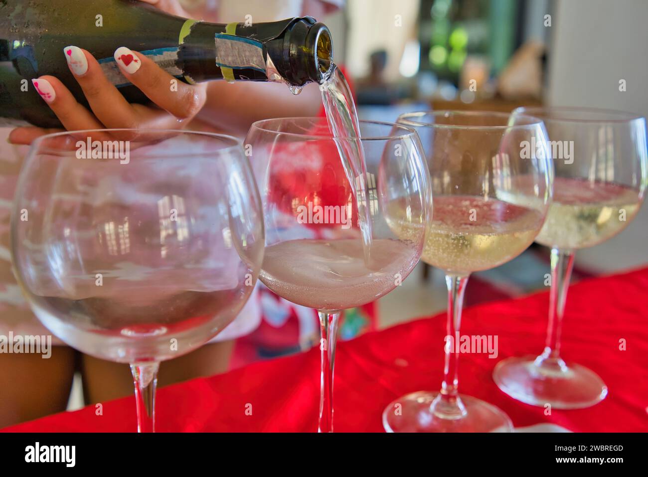 Femme à la main versant le vin mousseux prosecco dans des verres pendant la saison des fêtes Banque D'Images