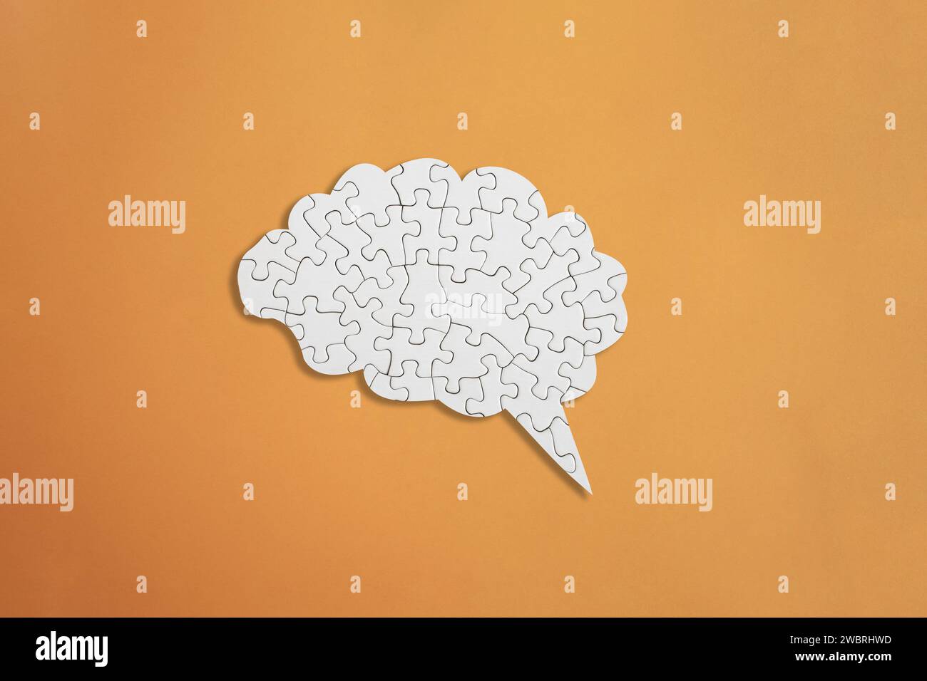Puzzle blanc en forme de cerveau sur fond orange, santé mentale et problèmes de mémoire Banque D'Images