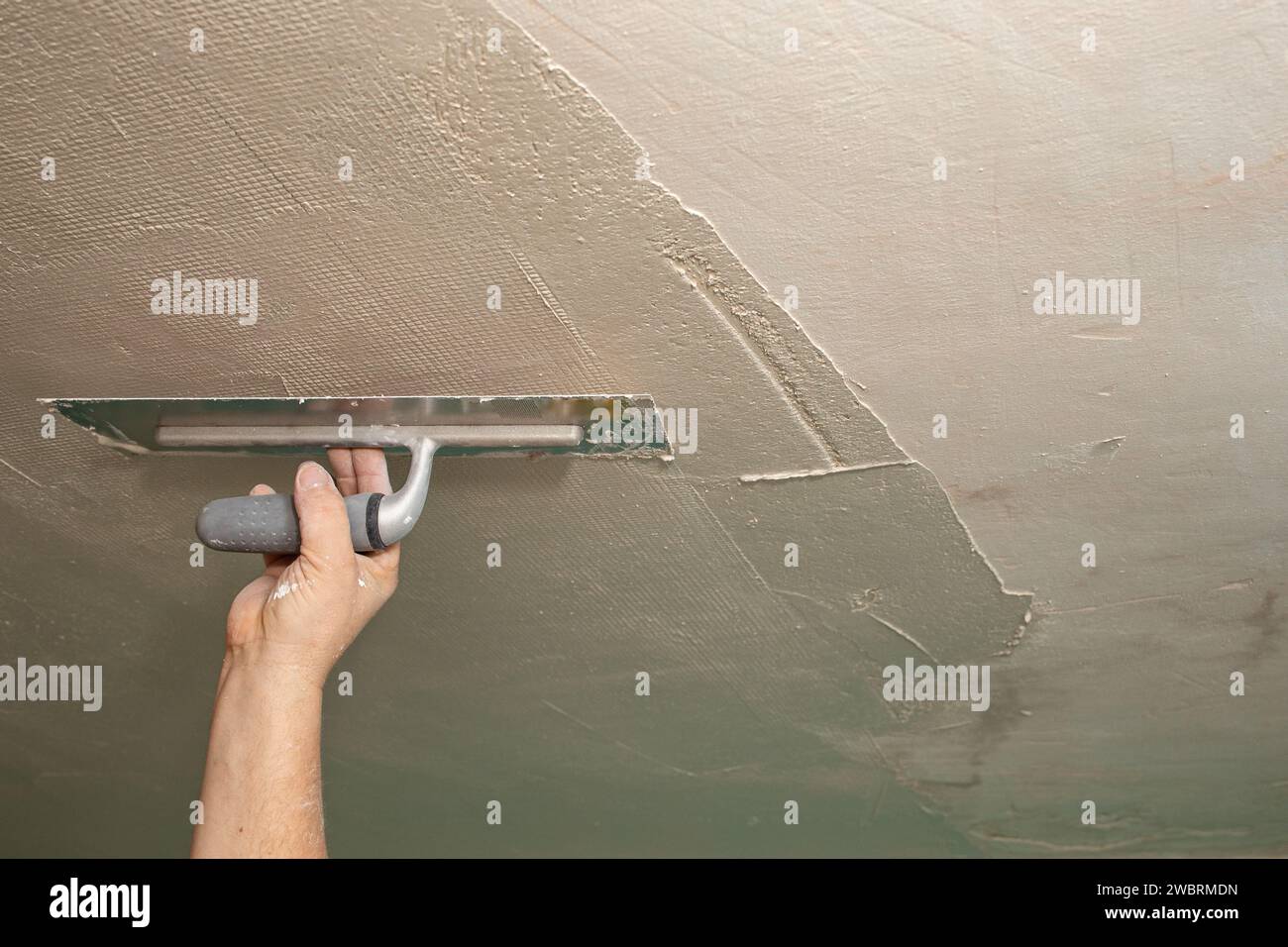 Main de constructeur avec une truelle fixant le plafond avec une maille, soft focus abstrait Banque D'Images