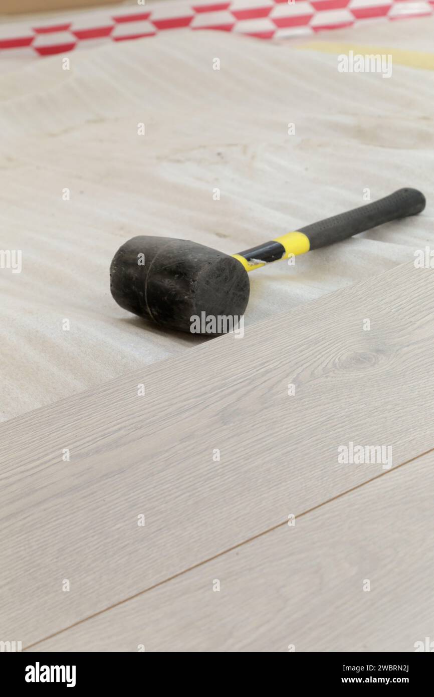 Marteau en caoutchouc pour l'installation d'un plancher en vinyle stratifié. Amélioration de la maison, nouvelle installation de plancher. Banque D'Images