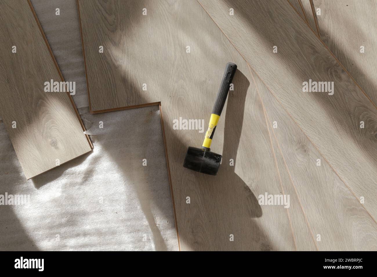 Marteau en caoutchouc pour l'installation d'un plancher en vinyle stratifié. Amélioration de la maison, nouvelle installation de plancher. Banque D'Images