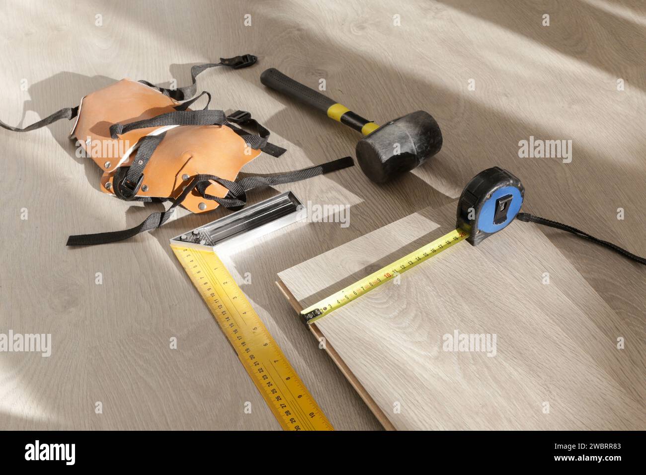 Marteau en caoutchouc, règle avec barre d'angle, mètre à ruban, scie sauteuse et autres outils pour l'installation du sol en vinyle stratifié. Amélioration de la maison, nouvelle installation de plancher Banque D'Images