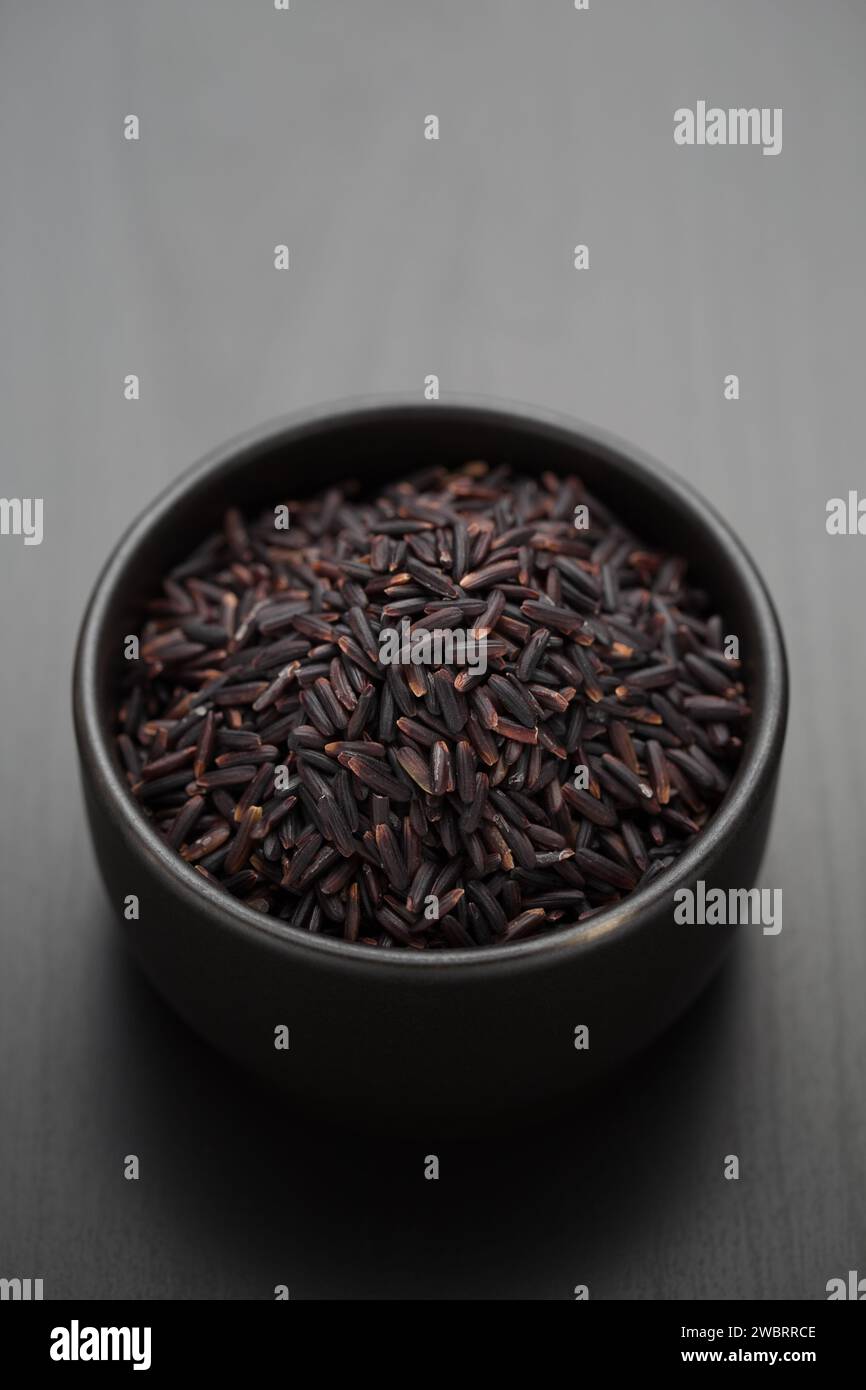 Riceberry dans un bol noir, matières premières alimentaires Banque D'Images
