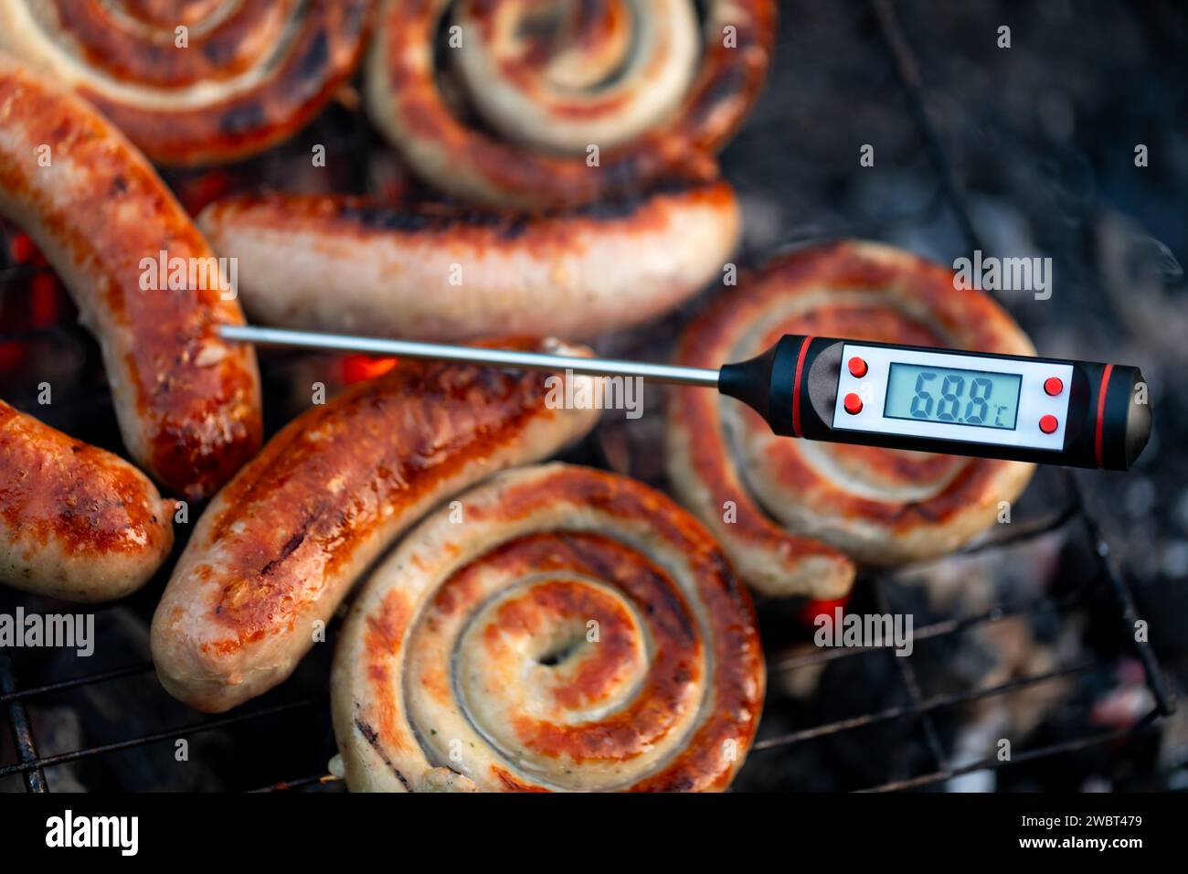 Gros plan d'un thermomètre à viande numérique affichant une température de cuisson sûre pour les saucisses grillées Banque D'Images