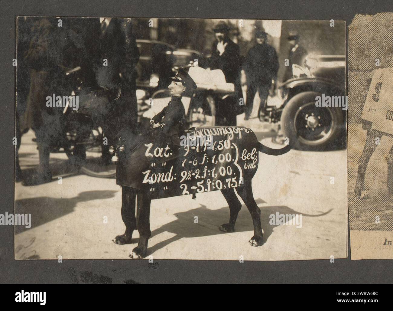 Chien du médecin marionnettiste avec texte publicitaire avec une poupée sur le dos, anonyme, 1930 - 1940 photographie cette photo fait partie d'un album. support photographique pour chien imprimé argentique à la gélatine. poupées pour adultes. publicité Banque D'Images