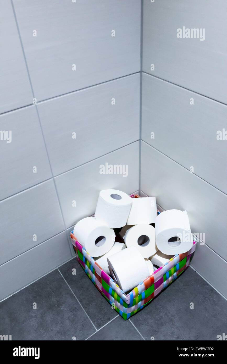 Une pile de rouleaux de papier toilette dans un panier coloré dans le coin d'une toilette ou d'une toilette Banque D'Images Une pile de rouleaux de papier toilette dans un panier coloré dans le coin d'une toilette ou d'une toilette Banque D'Images