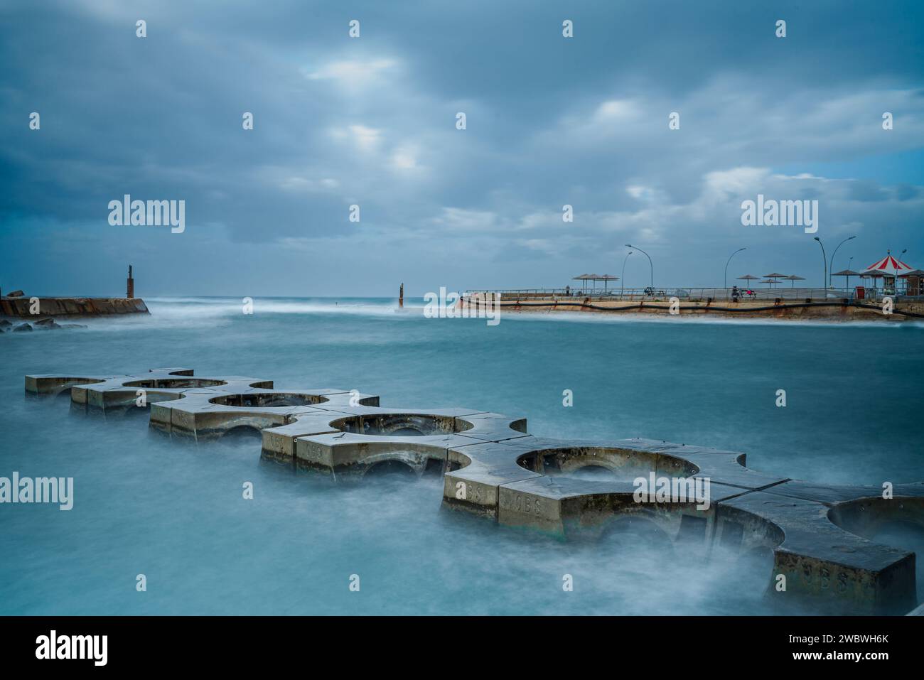 Un mur de brise-lames pittoresque situé au milieu de l'immensité de l'océan, avec un spectacle enchanteur de vagues s'écrasant contre lui Banque D'Images