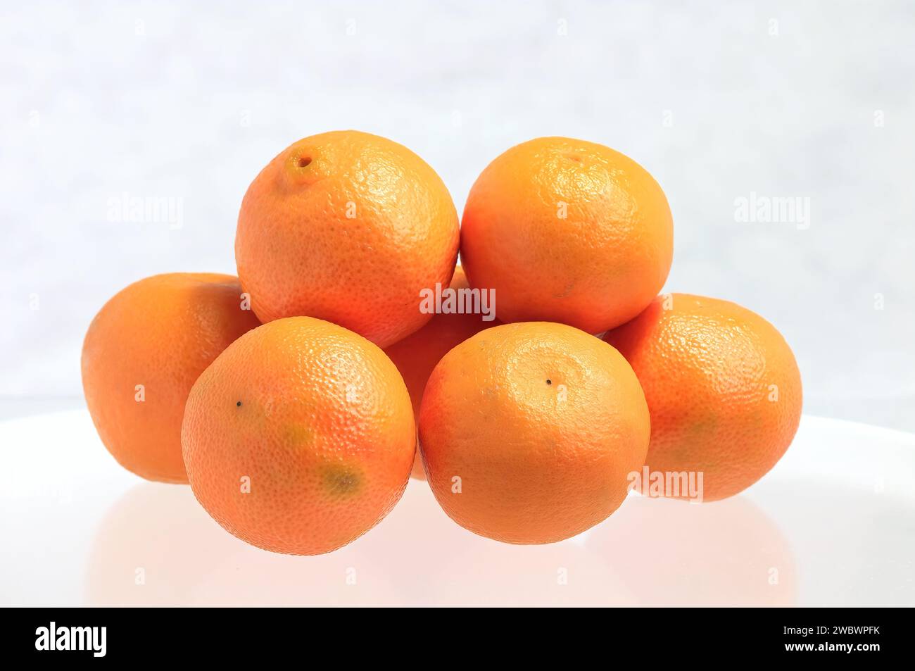 Oranges navel (Citrus x sinensis) - fruits entiers empilés sur fond blanc. Banque D'Images