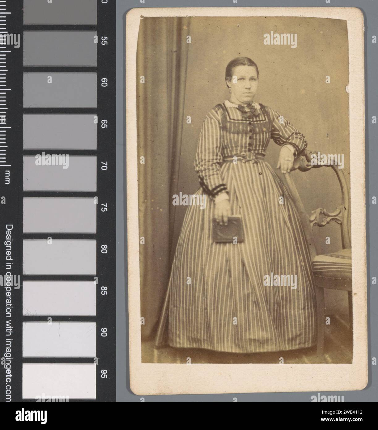 Portrait d'une jeune femme inconnue avec un livre près d'une chaise, Bernardus Petrus Rabels, 1870 - 1893 Photographie. Carte visite Amsterdam Cardboard. papier albumen print adolescent, jeune femme, jeune fille. Une personne historique anonyme a représenté Amsterdam Banque D'Images