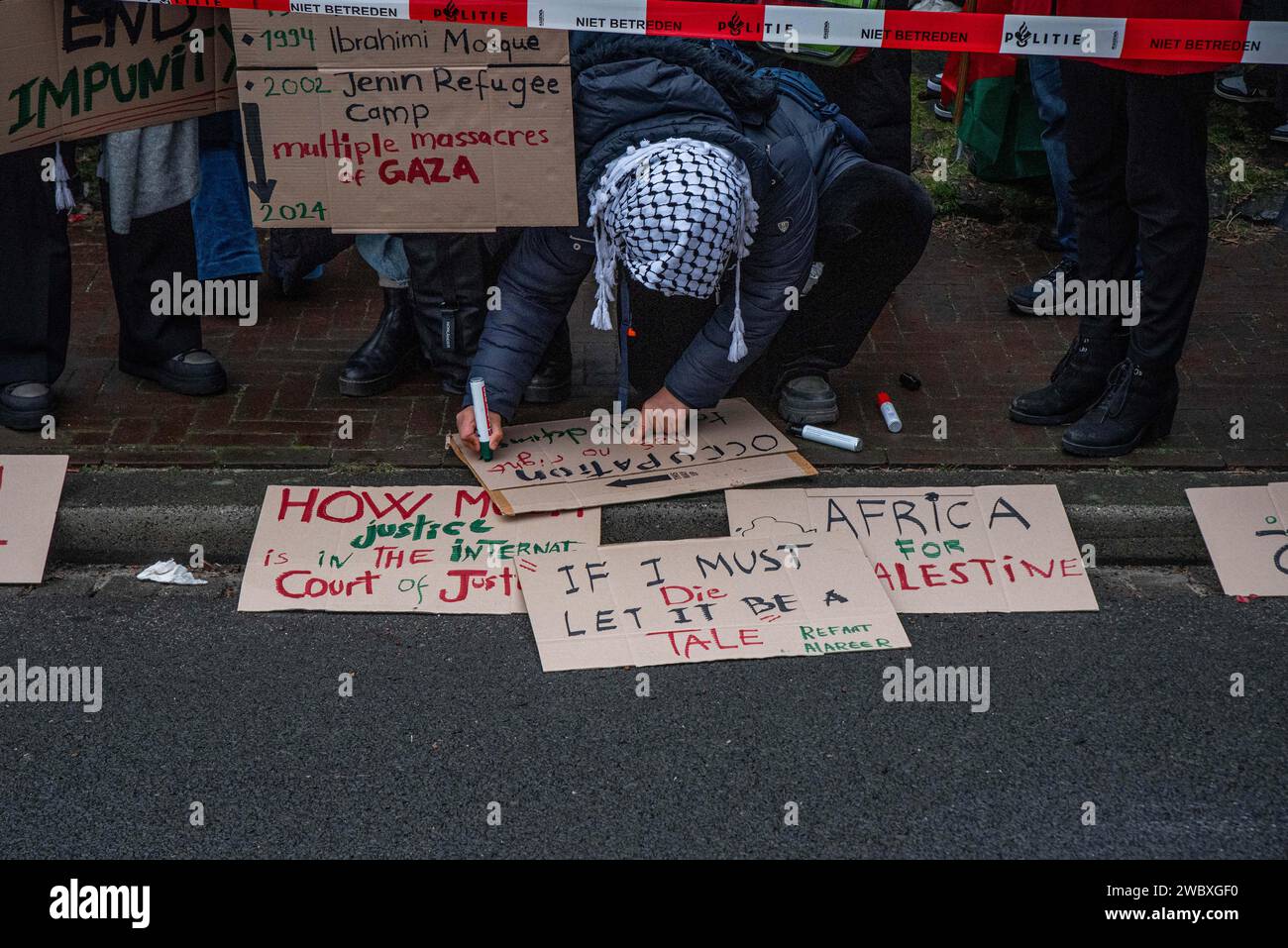 La Haye, Hollande du Sud, pays-Bas. 12 janvier 2024. Un manifestant pro-palestinien écrit un panneau de protestation. Le 12 janvier 2024, des militants pro-israéliens et pro-palestiniens ont manifesté devant la Cour internationale de Justice à la Haye. À l'intérieur de la Cour, Israël s'est défendu contre l'accusation de génocide de l'Afrique du Sud. (Image de crédit : © James Petermeier/ZUMA Press Wire) USAGE ÉDITORIAL SEULEMENT! Non destiné à UN USAGE commercial ! Banque D'Images